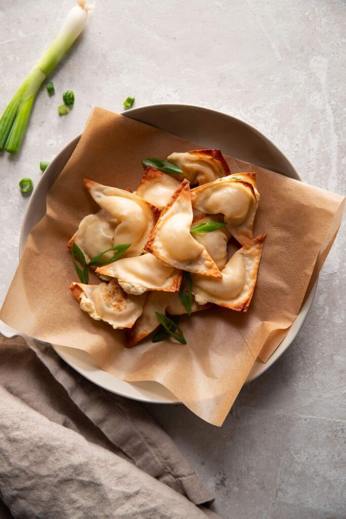 cream cheese wontons in a bowl with green onions on top