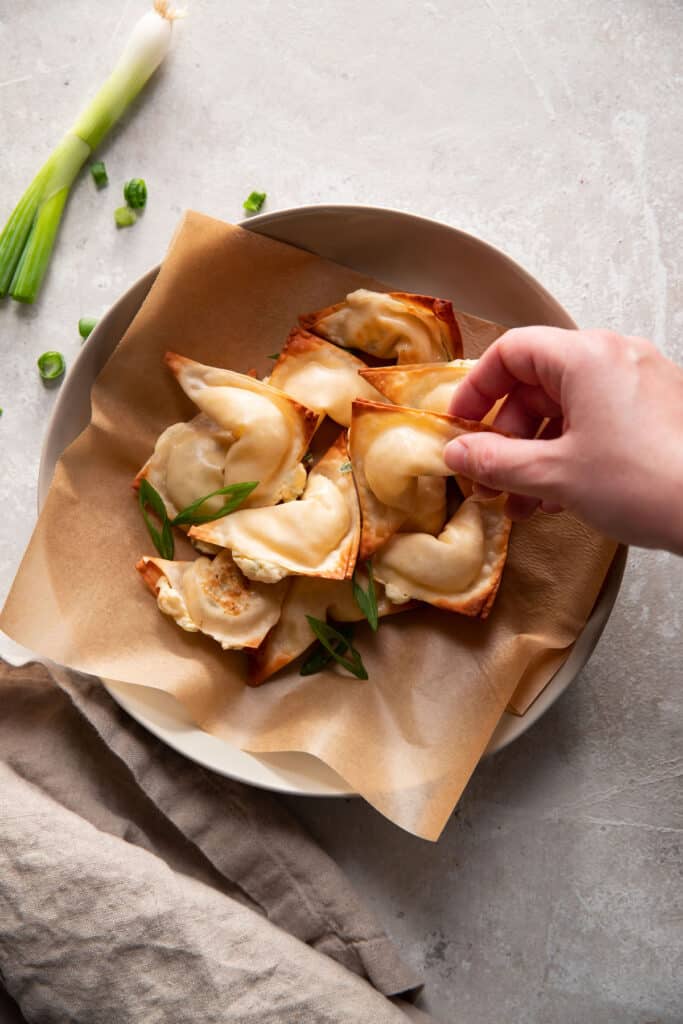 cream cheese wontons in a bowl with green onions on top