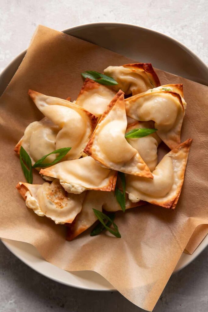 cream cheese wontons in a bowl with green onions on top