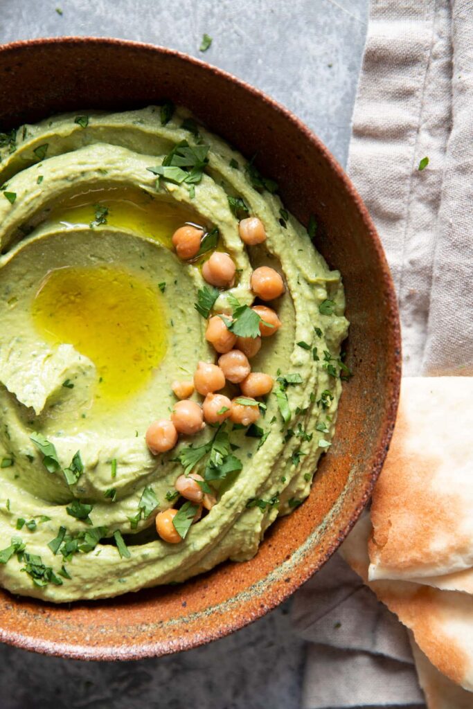 cilantro jalapeno hummus in a bowl with olive oil drizzled in the center