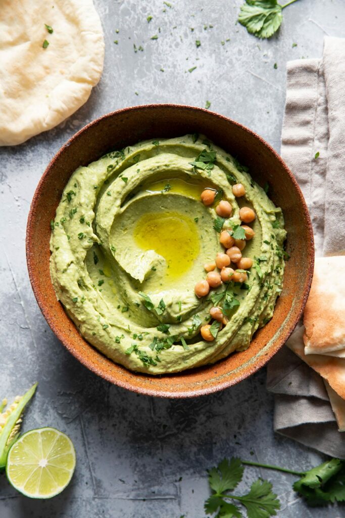 bowl of cilantro jalapeno hummus with olive oil drizzle and chickpea garnish