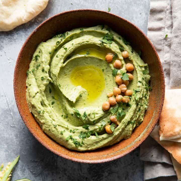 bowl of cilantro jalapeno hummus with olive oil drizzle and chickpea garnish