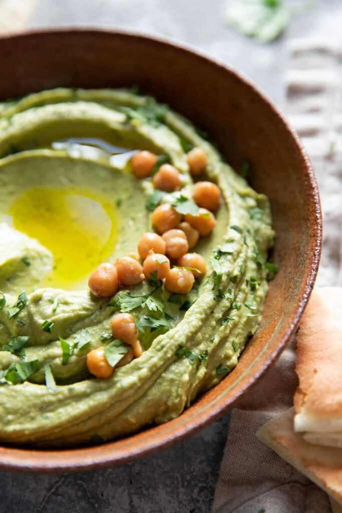 bowl of cilantro jalapeno hummus with olive oil drizzle and chickpea garnish