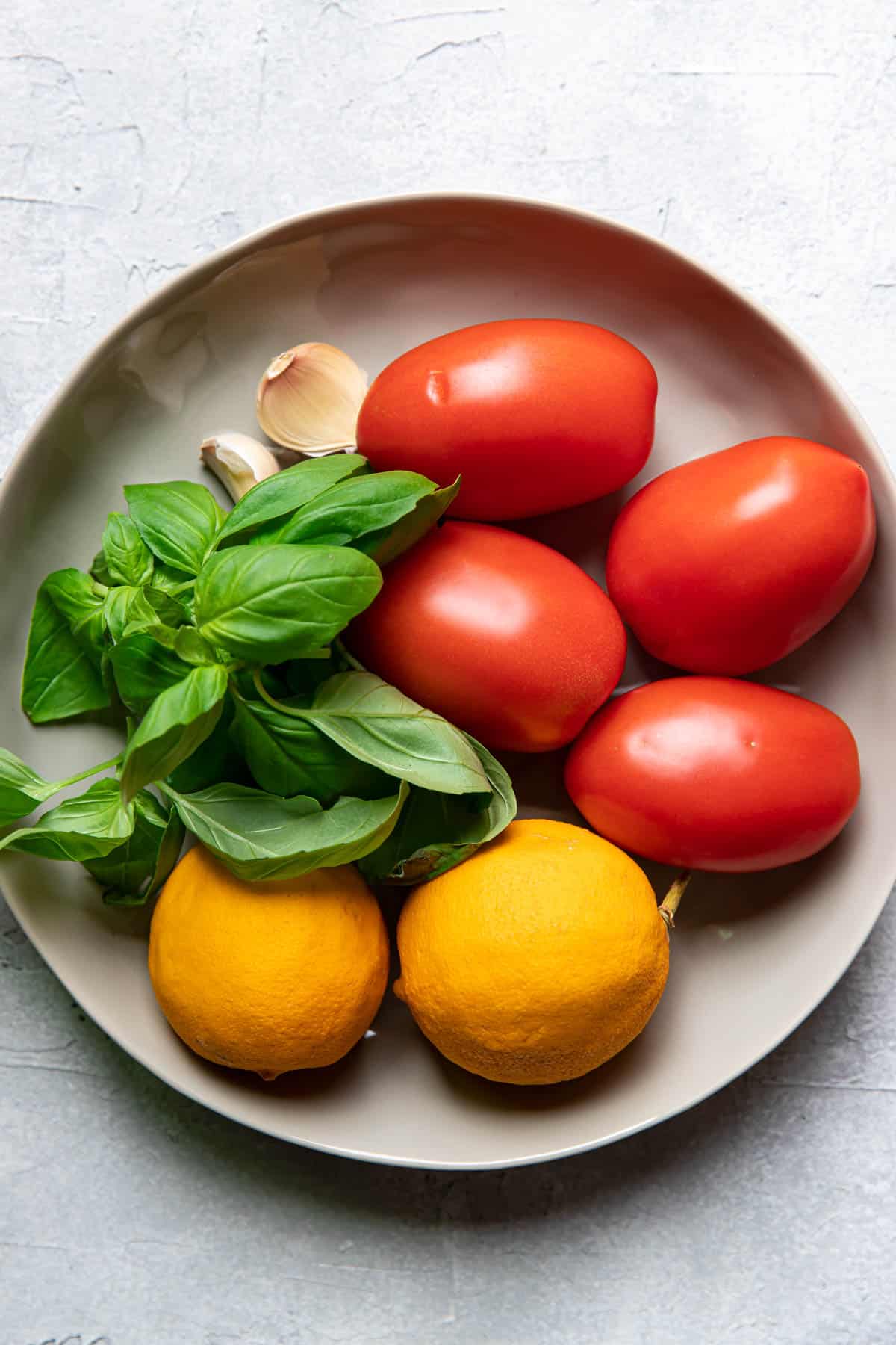 Bowl of tomatoes, lemons, basil and garlic.