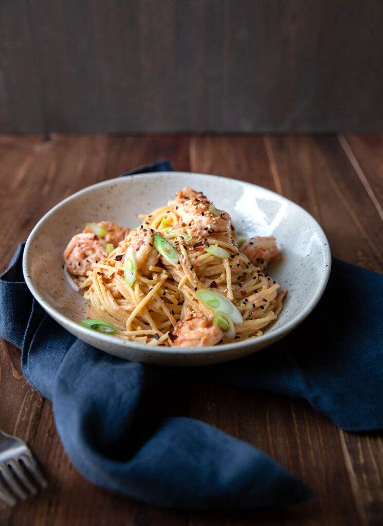 spicy bang bang shrimp pasta and green onions in a bowl