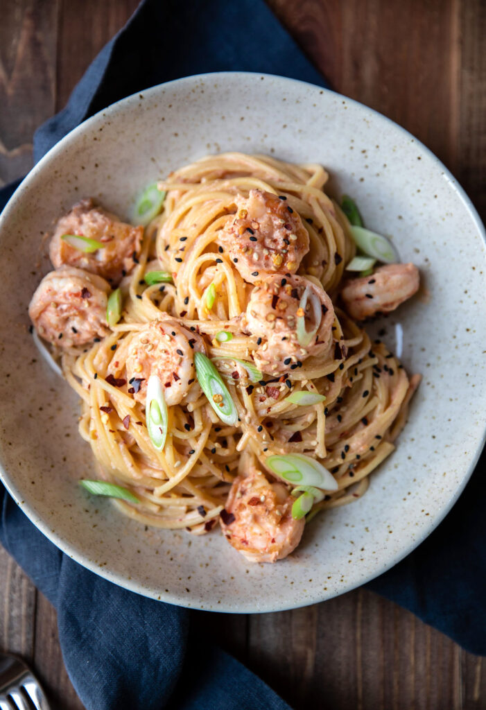 spicy bang bang shrimp pasta and green onions in a bowl