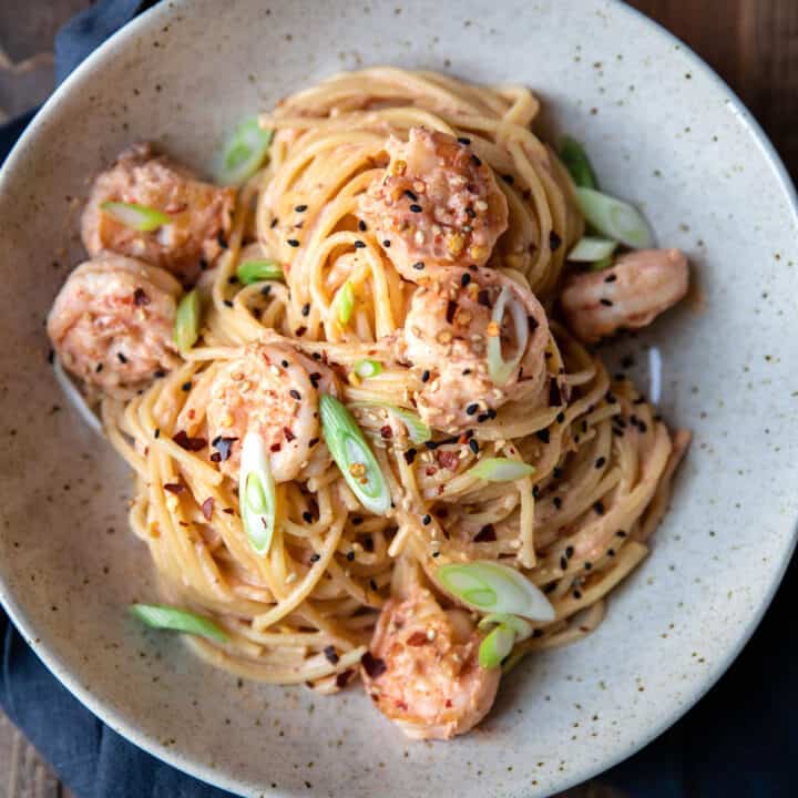 spicy bang bang shrimp pasta and green onions in a bowl