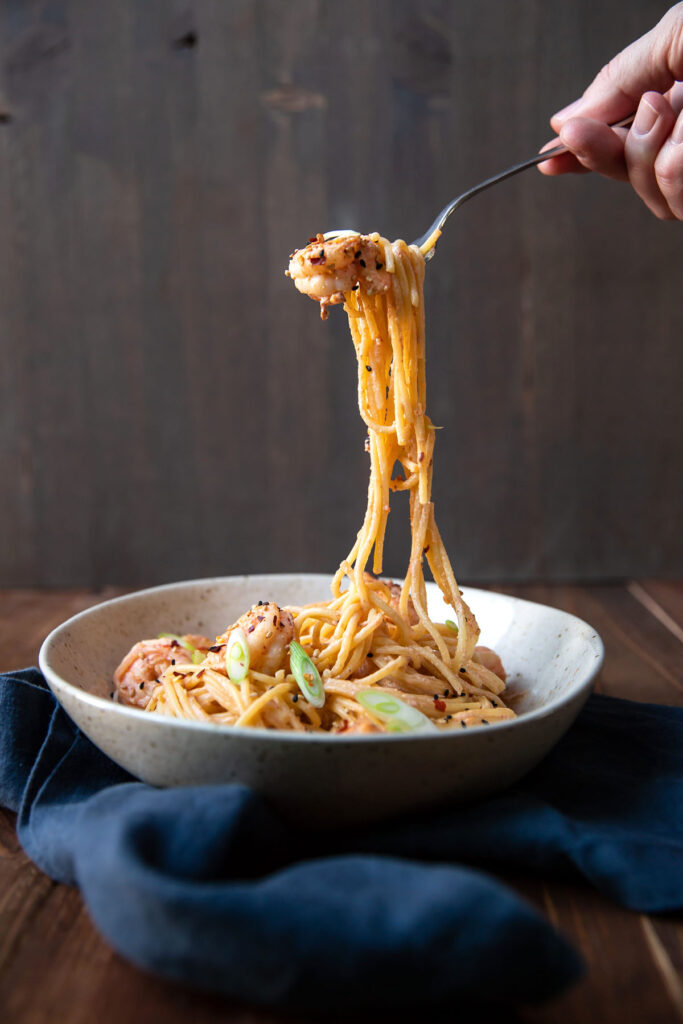 spicy bang bang shrimp pasta and green onions in a bowl