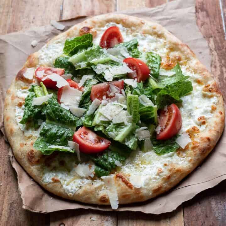 caesar salad pizza on a table.