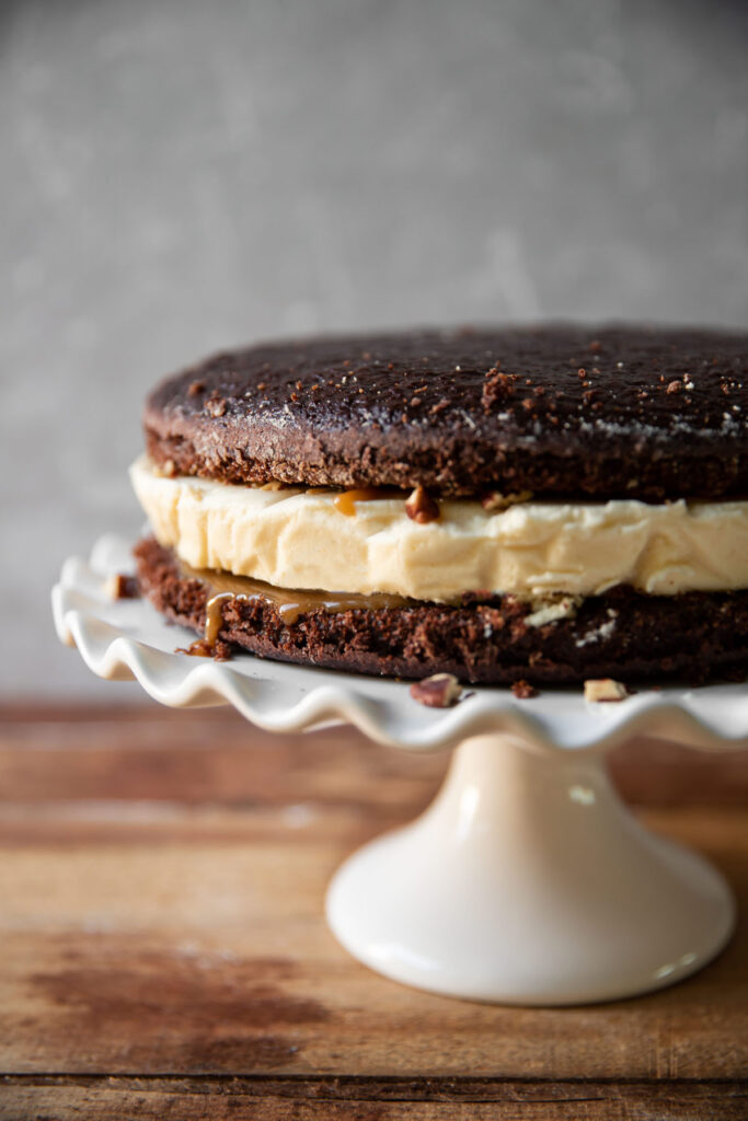 Cheesecake layered between chocolate cake and salted caramel with pecans