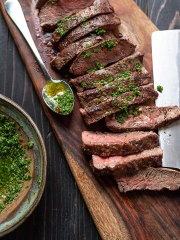 flat iron steak with chimichurri sauce on a cutting board