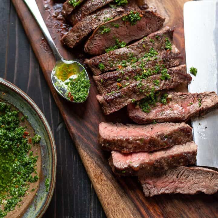 flat iron steak with chimichurri sauce on a cutting board