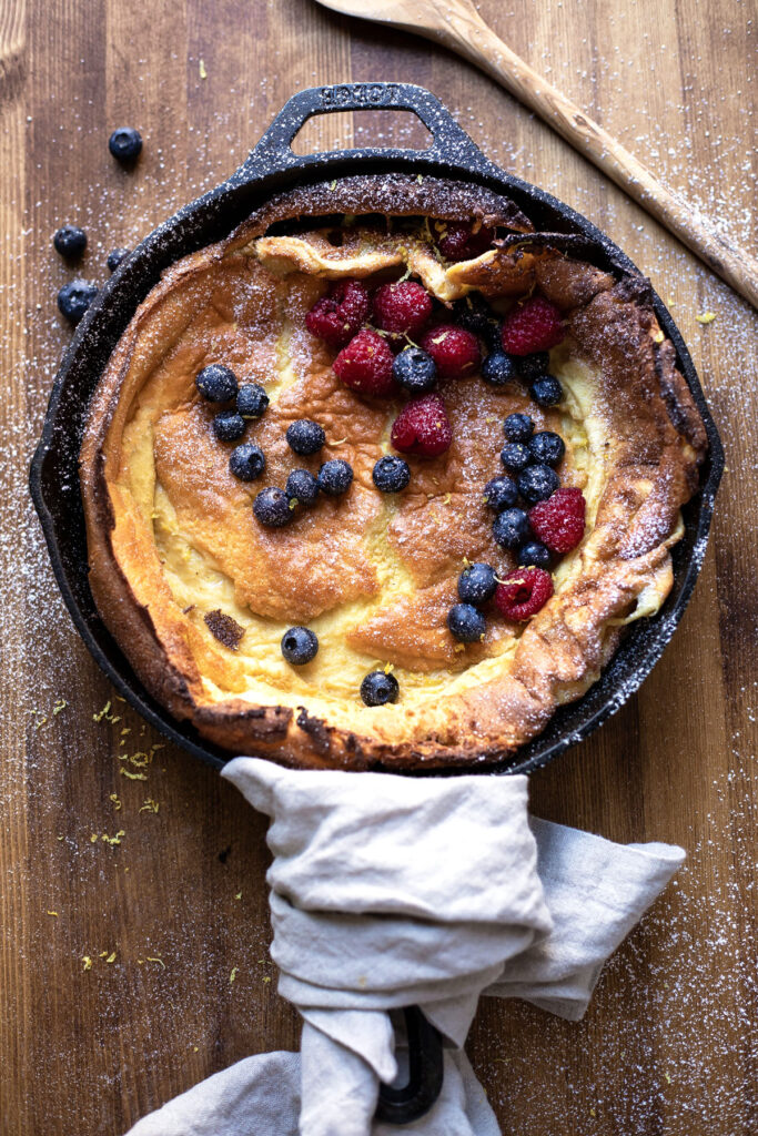skillet dutch baby with lemon zest blueberries and raspberries