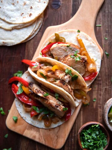 chicken fajitas with bell peppers on a cutting board