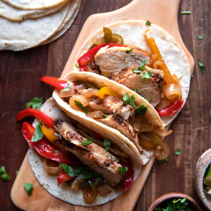 chicken fajitas with bell peppers on a cutting board