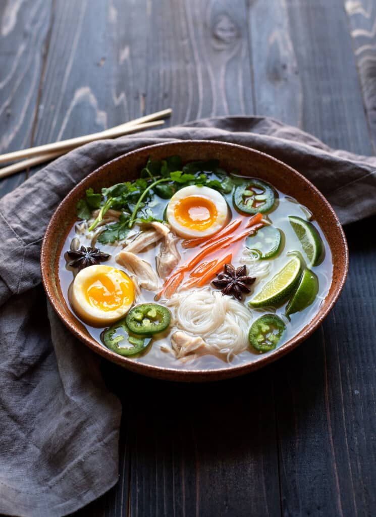 bowl of chicken pho with soft boiled egg jalapeno cilantro rice noodles