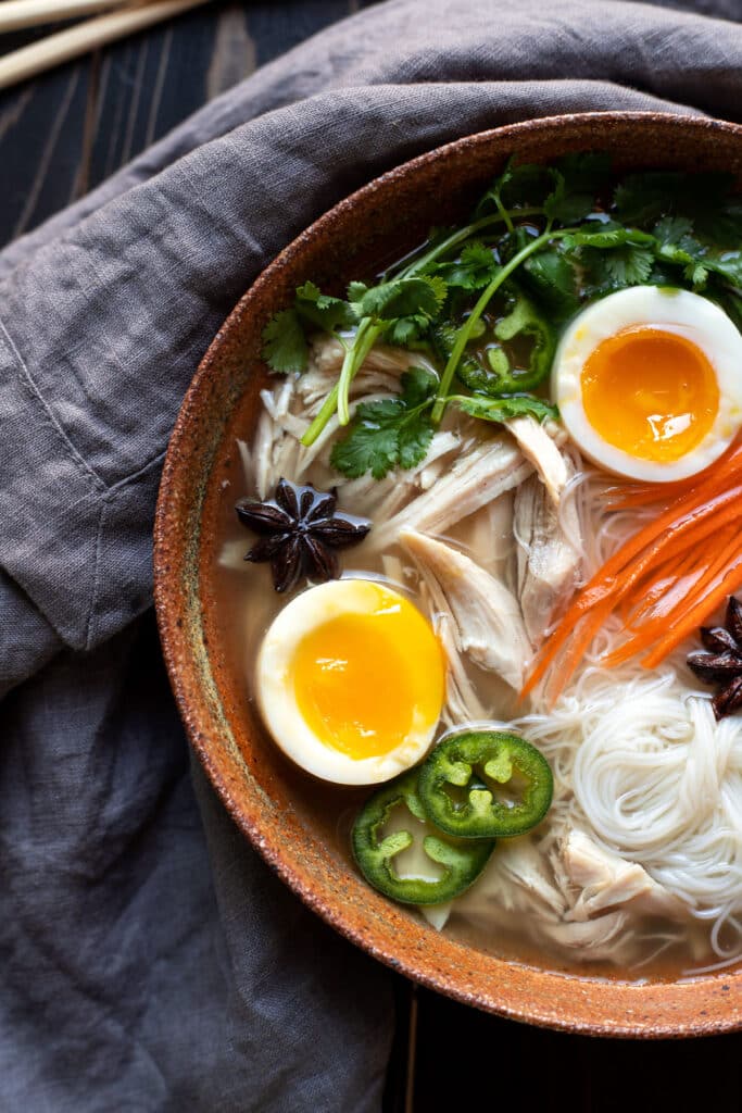 bowl of chicken pho with soft boiled egg jalapeno cilantro rice noodles