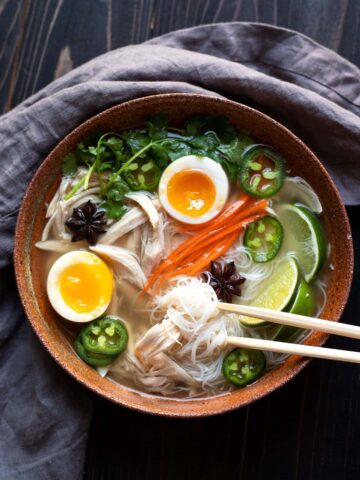 bowl of chicken pho with soft boiled egg jalapeno cilantro rice noodles