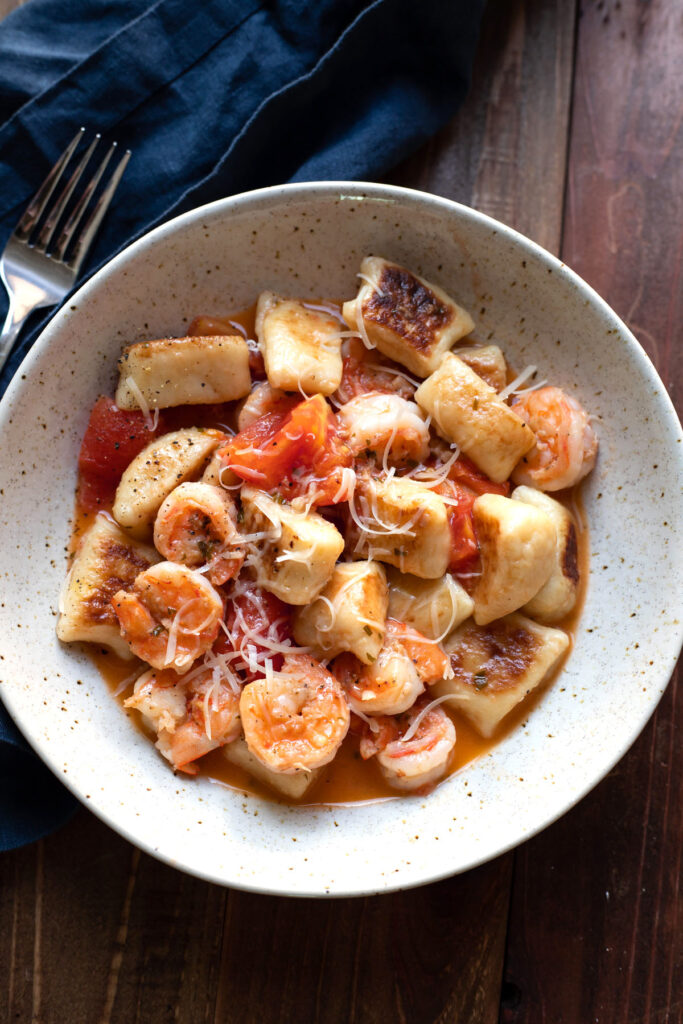 gnocchi with tomatoes and a white wine sauce in a bowl