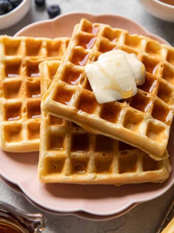 buttermilk waffles covered in syrup on a plate.