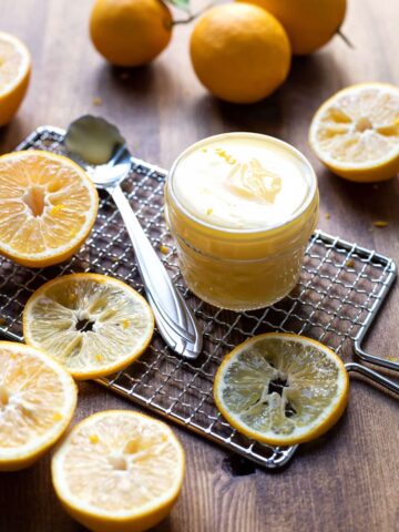 lemon curd in a jar with lemon slices around it