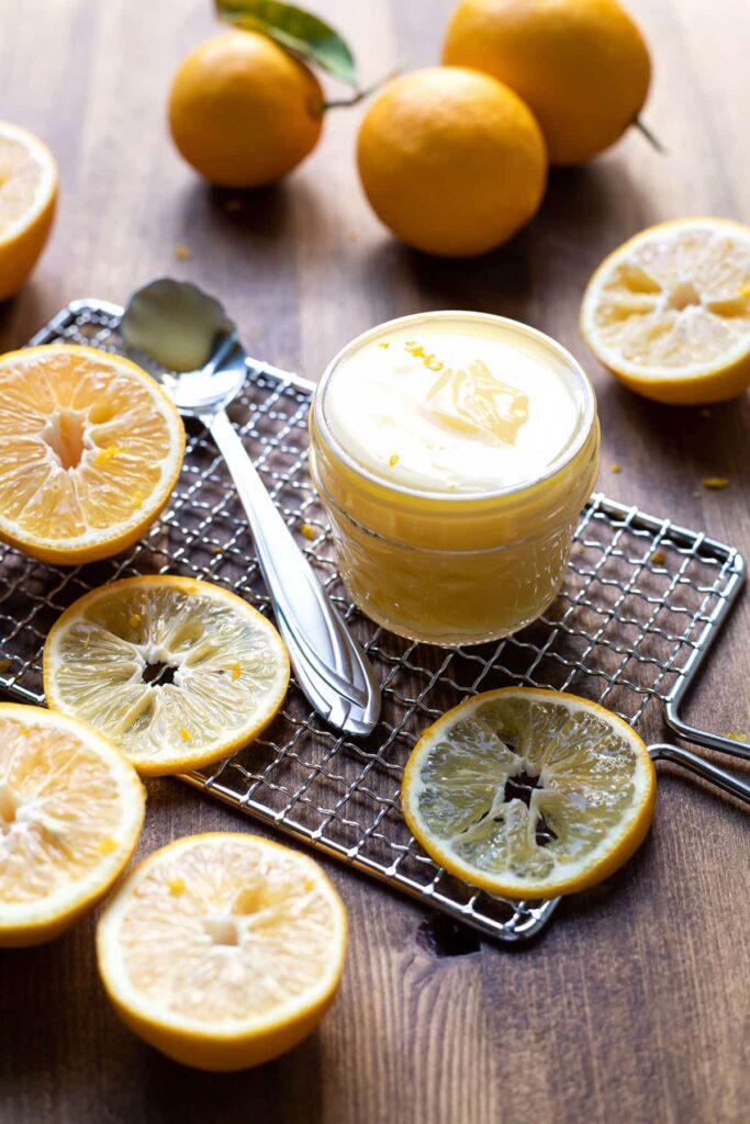 lemon curd in a jar with lemon slices around it