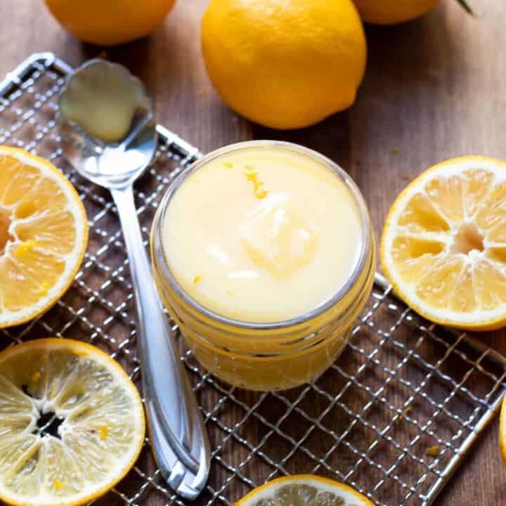 lemon curd in a jar with lemon slices around it