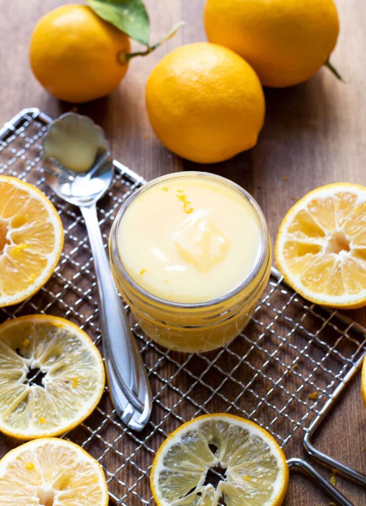 lemon curd in a jar with lemon slices around it