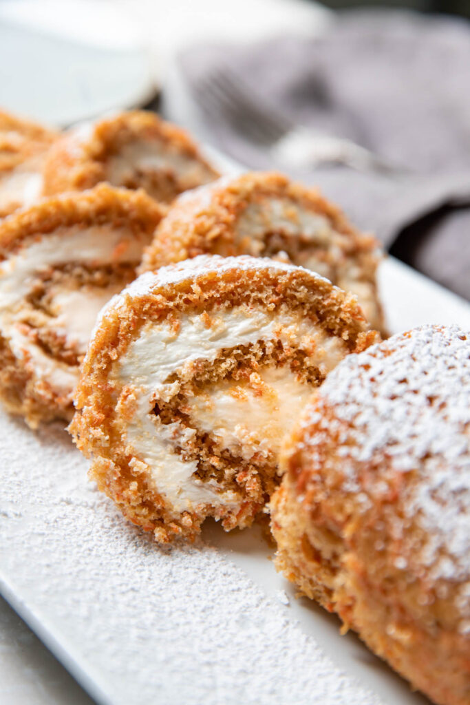 Carrot cake in a roll cake form with cream cheese frosting.