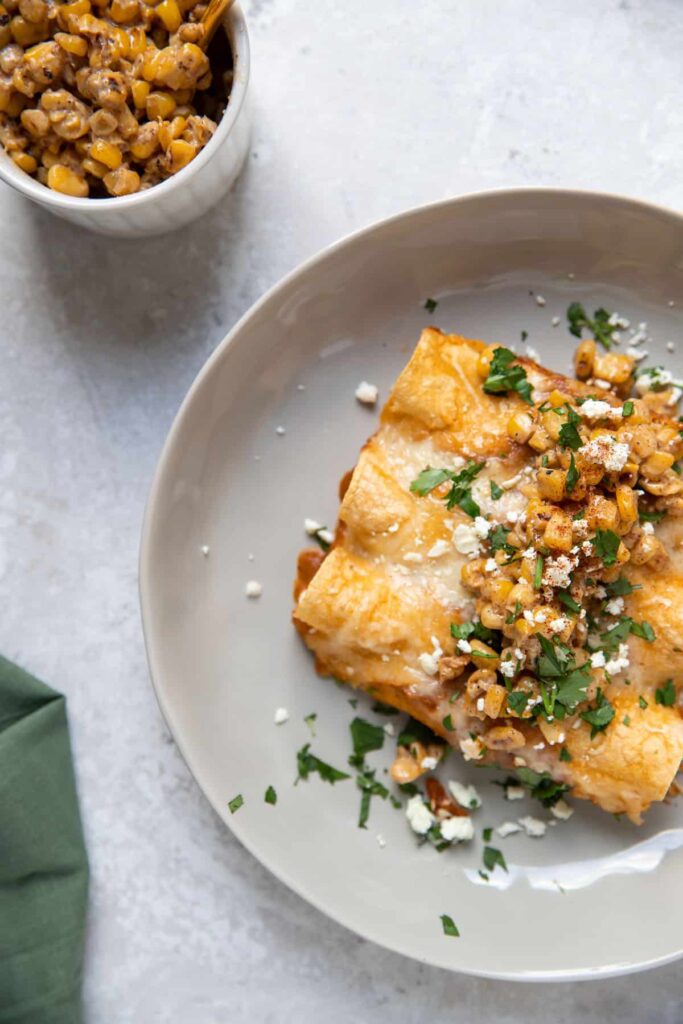 plate of chicken enchiladas with cilantro cotija cheese and elote corn