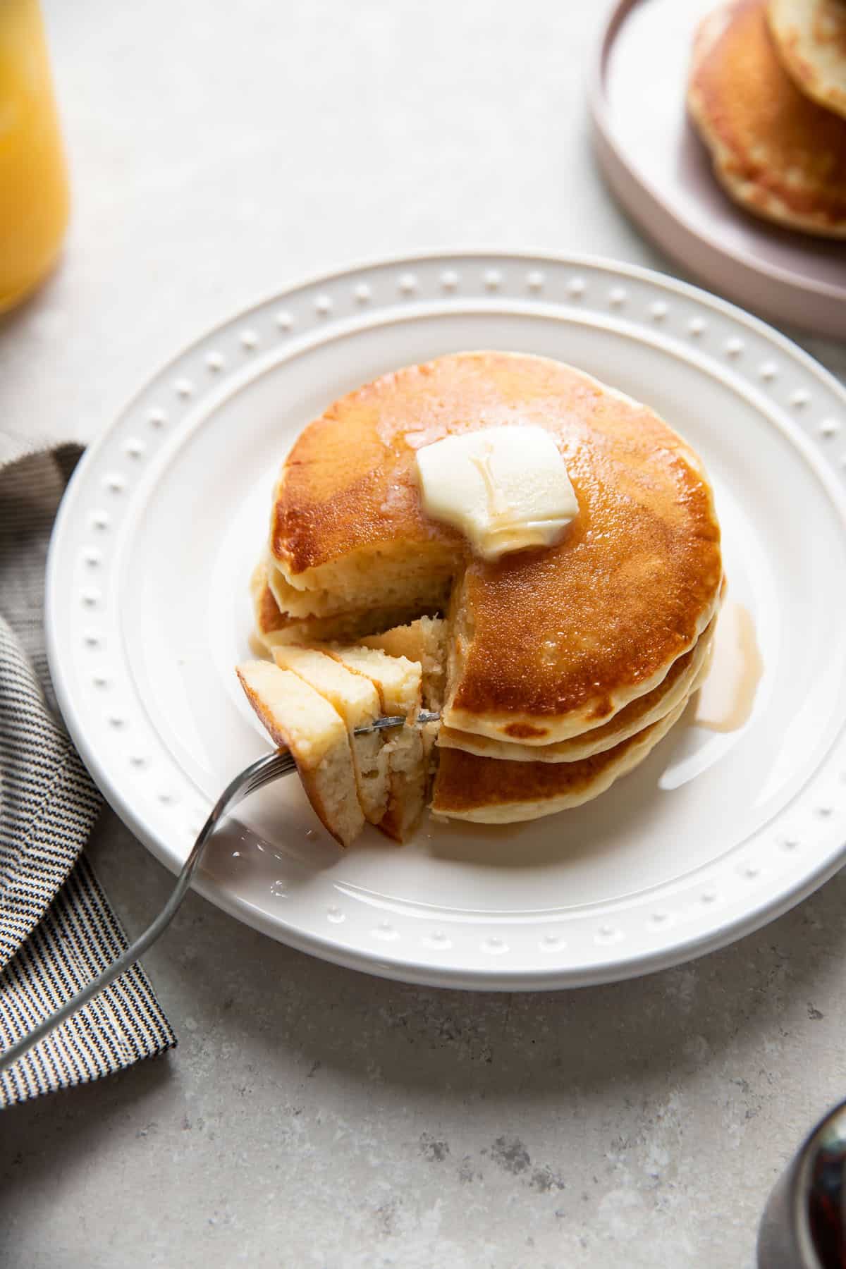 buttermilk pancakes on a plate with butter and maple syrup on top