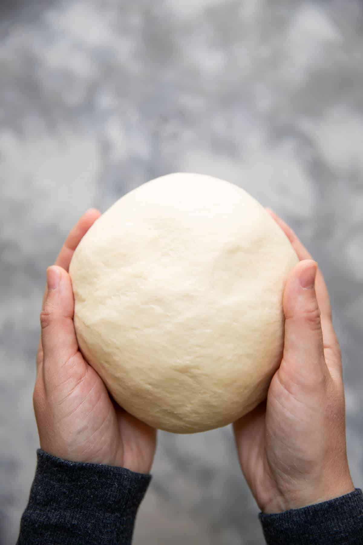 hands holding a ball of dough for soft pretzels