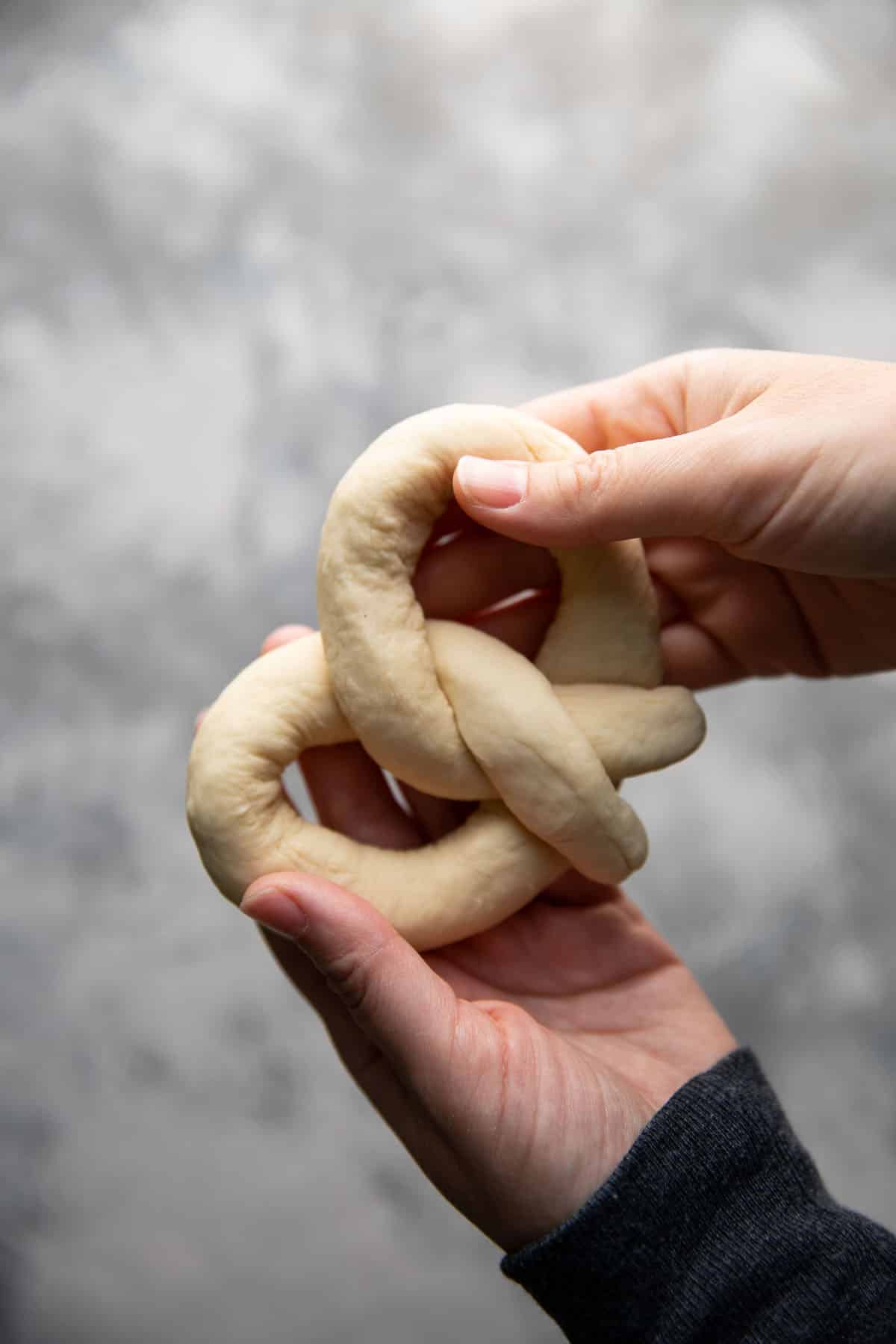 hand holding an uncooked soft pretzel