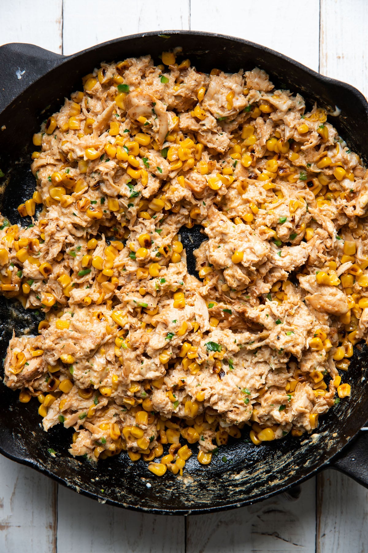 shredded chicken and mexican street corn mixed together in a skillet