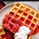 belgian waffles with strawberries and whipped cream on a plate