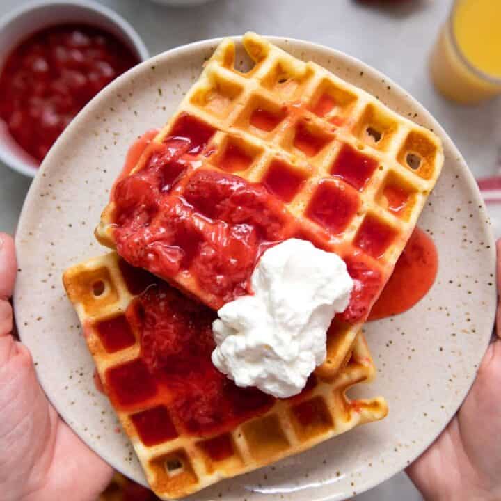 belgian waffles with strawberries and whipped cream on a plate