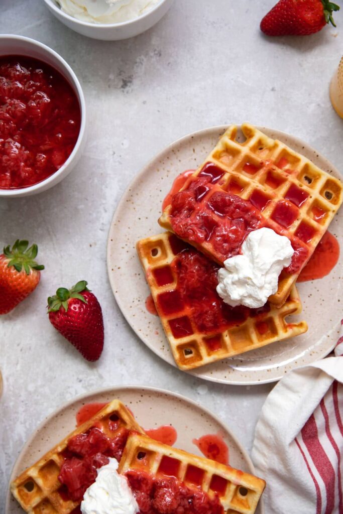 belgian waffles with strawberries and whipped cream on a plate