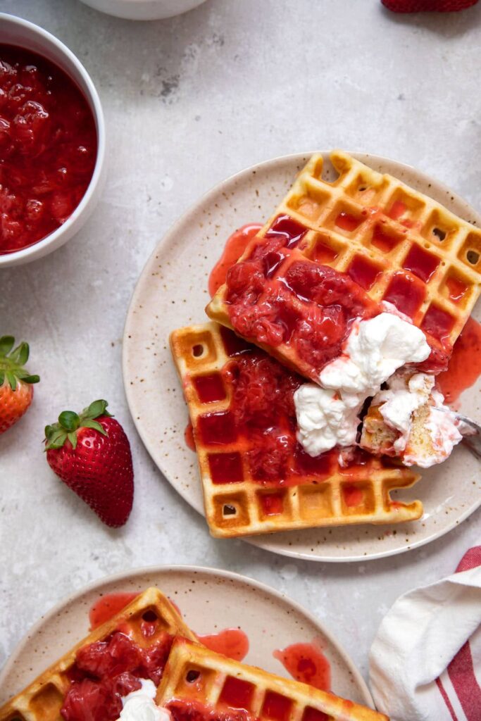 belgian waffles with strawberries and whipped cream on a plate