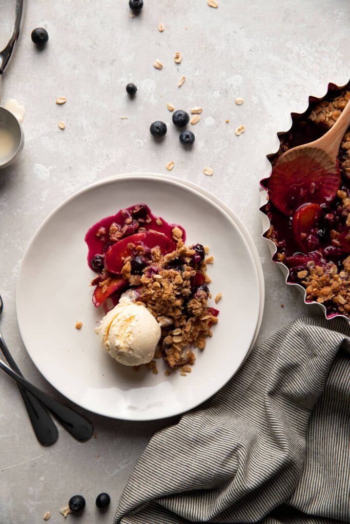 Plate of blueberry peach crisp with vanilla ice cream