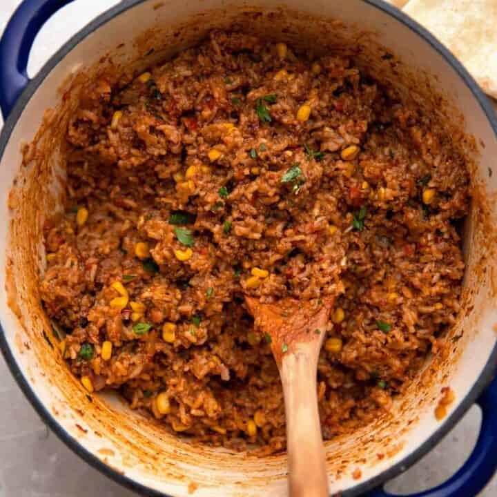 mexican beef and rice in a cast iron pot with tortillas on the side