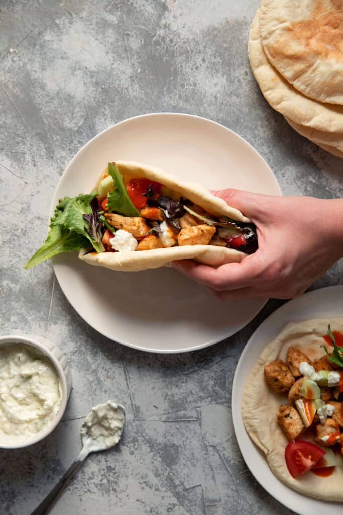 chicken pitas on a plate with tomato lettuce and tzatziki sauce