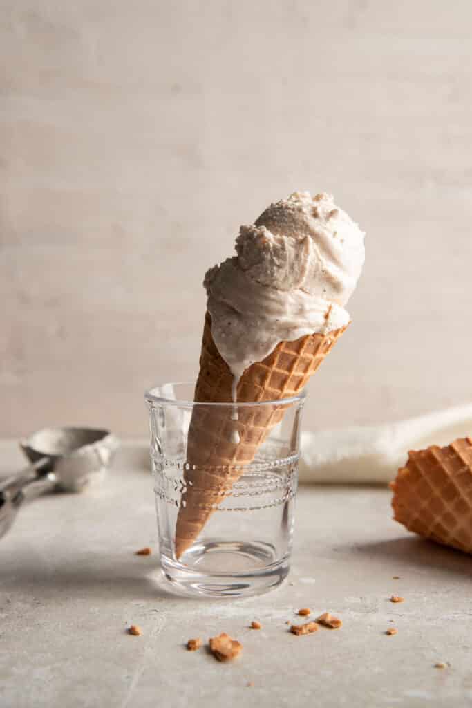 chai ice cream in a waffle cone held up by a clear drinking glass