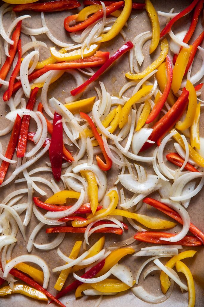 sliced bell peppers and onions on a sheet pan