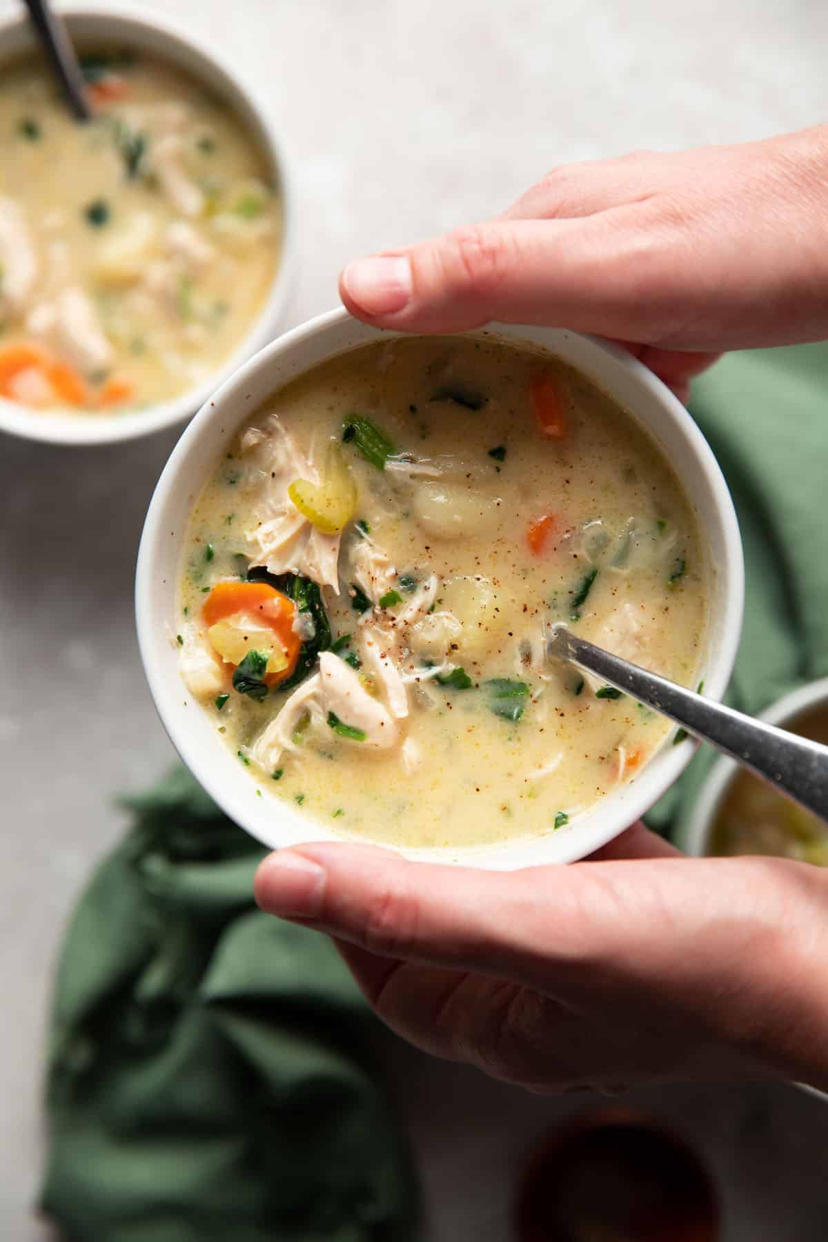 gnocchi soup with vegetables in a white bowl
