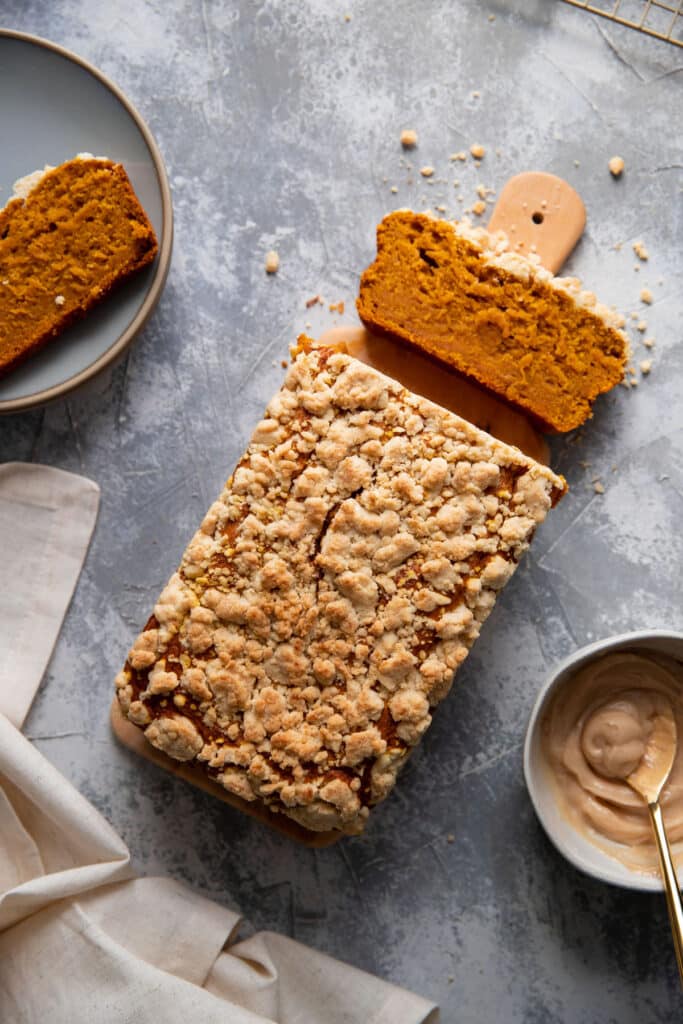 pumpkin loaf on a wood board with a slice cut off of it