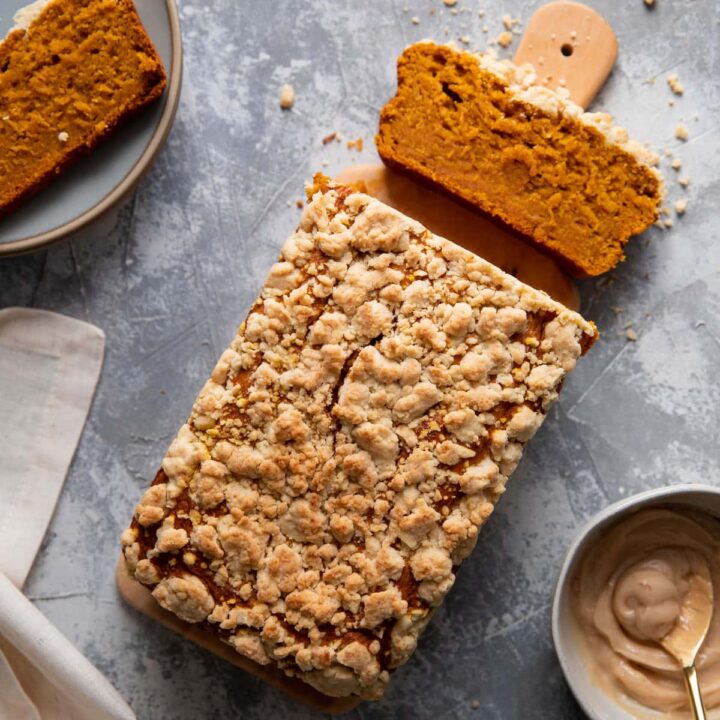 pumpkin loaf on a wood board with a slice cut off of it