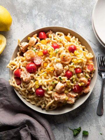 fusili pasta with shrimp corn and tomatoes in a bowl