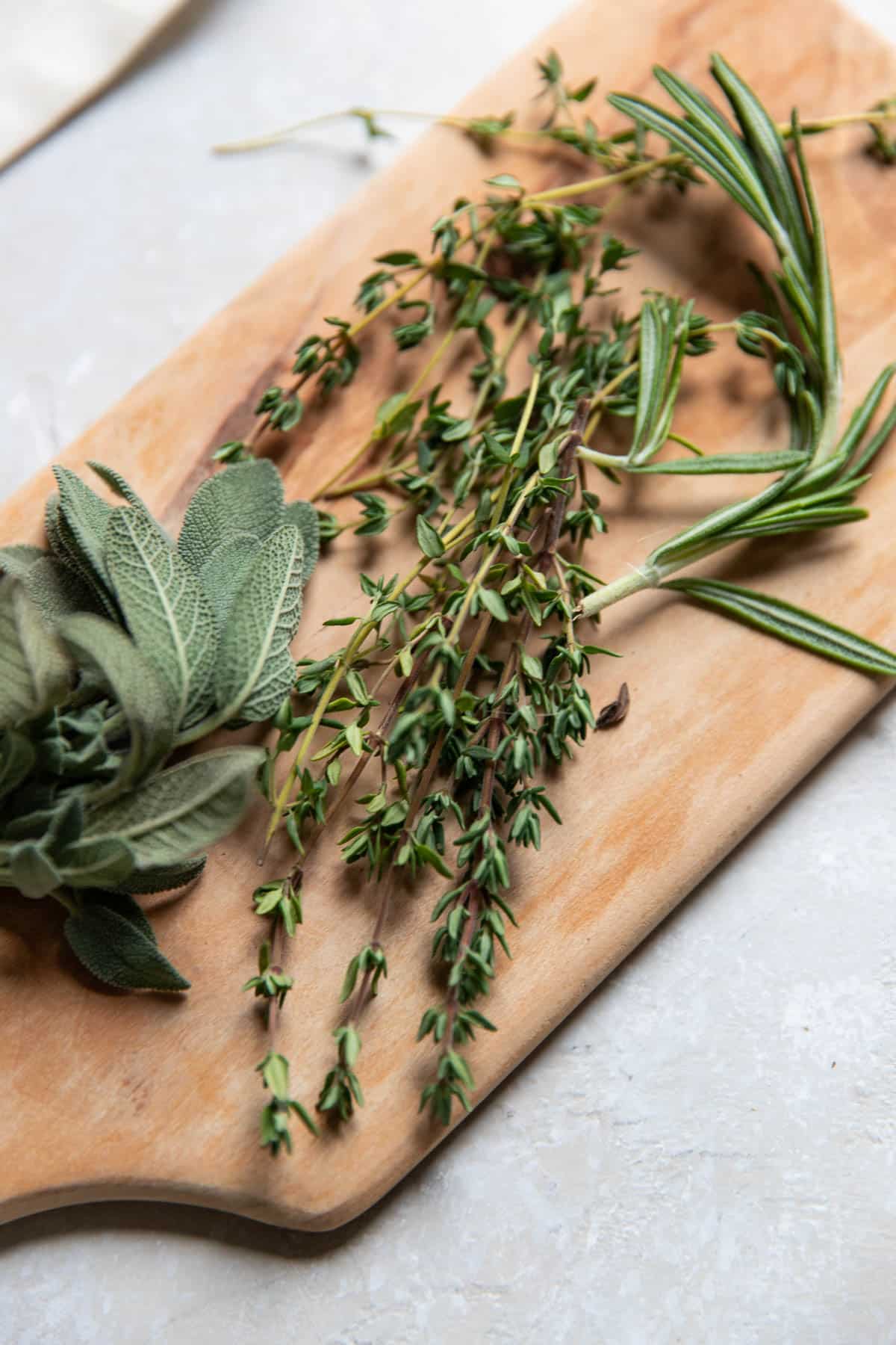 rosemary sage and thyme on a wooden cutting board