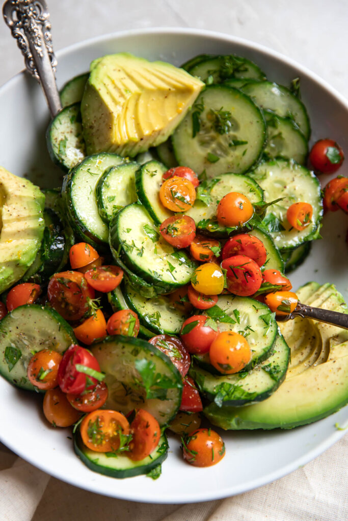 Up close image of a cucumber avocado salad with tomatoes.
