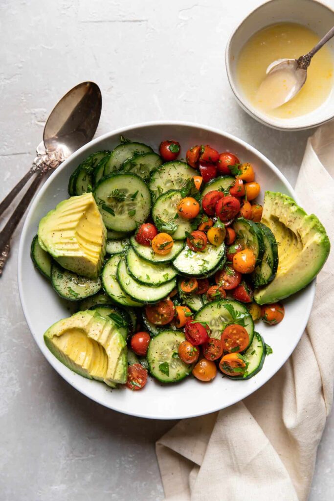 Up close image of a cucumber avocado salad with tomatoes.